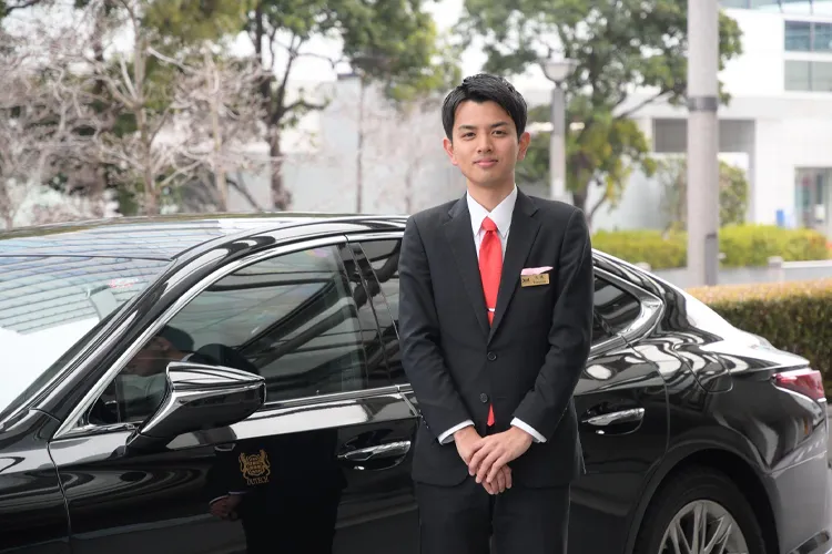 A chauffeur standing in front of a private hire vehicle