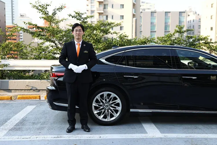 A chauffeur standing in front of a private hire vehicle
