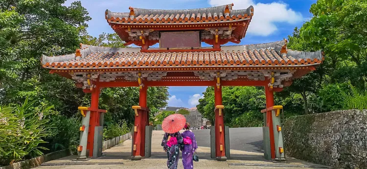 Two women standing in front of the gate of Shuri Castle