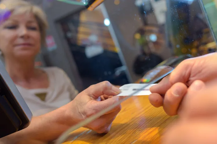 Customer taking ticket from under glass hatch